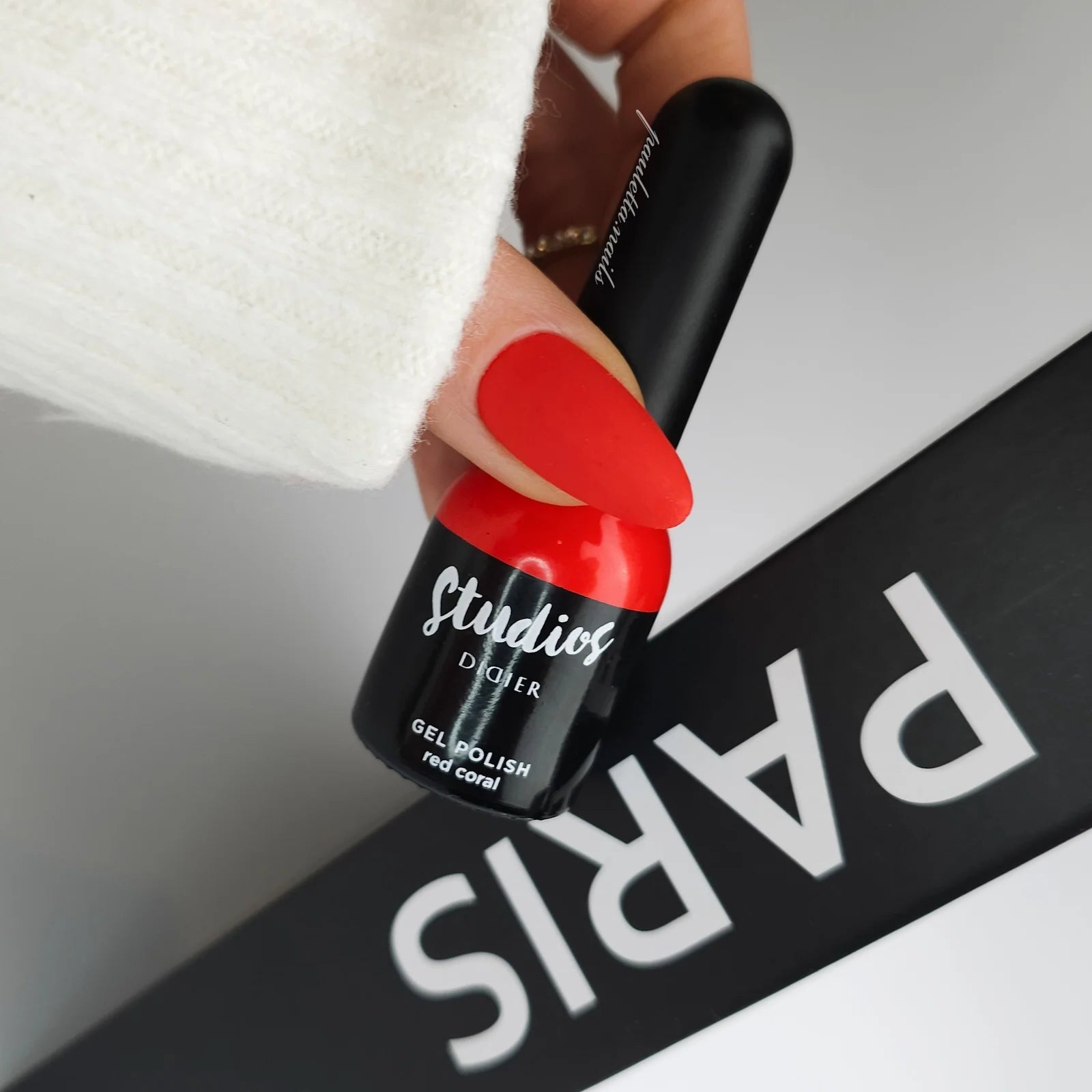 Hand holding a red nail polish bottle with 'Didier Lab Gel Polish Studio' branding against a 'PARIS' background.